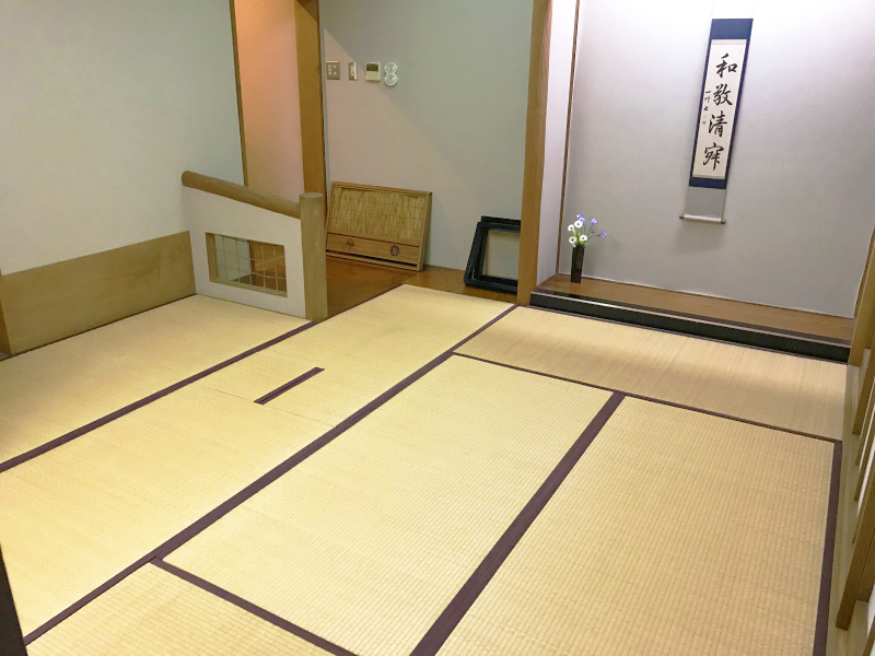 畳が敷かれ壁に掛け軸が飾ってある茶室の写真