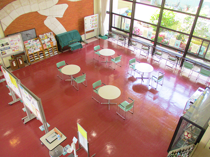 赤い床にたくさんのテーブルと椅子が並べられたロビーの写真