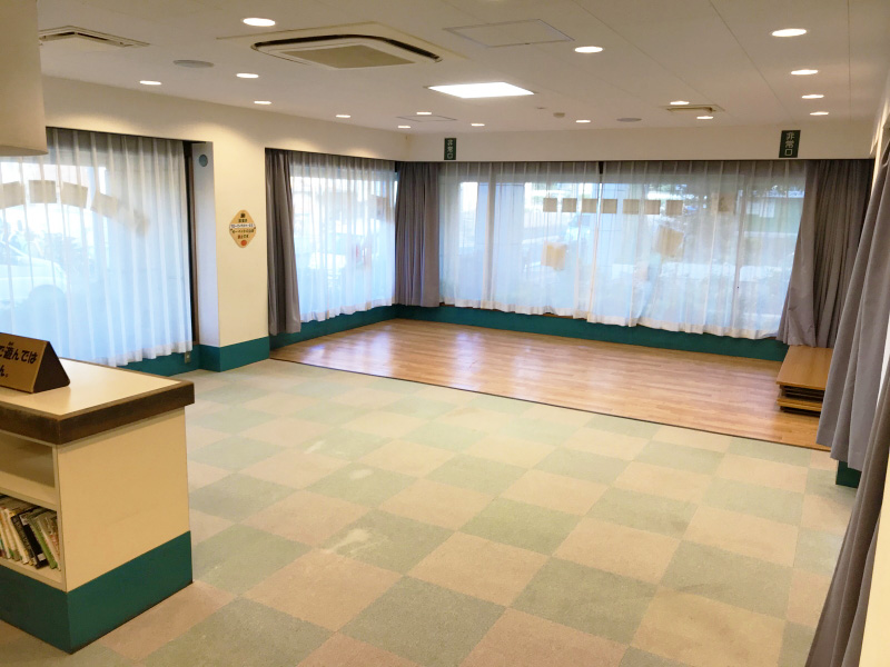 大きな窓と緑色とベージュ色のタイルマットが格子状に敷かれた部屋の写真