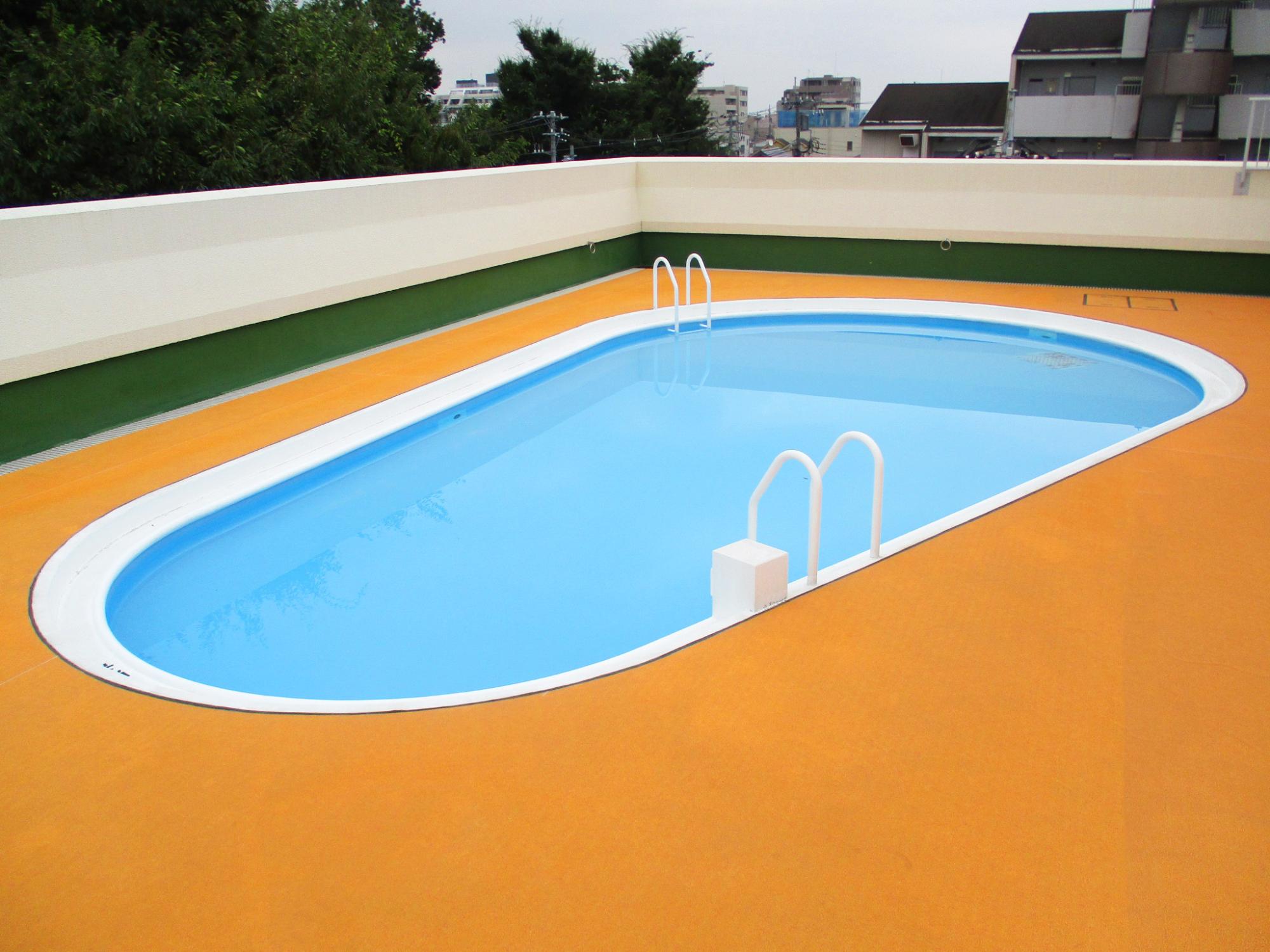 オレンジ色のプールサイドの楕円形プールの写真