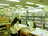 たくさんの本が並んでいる中で本を読んでいる人の写真