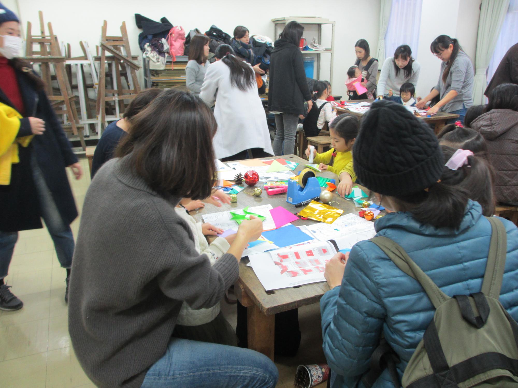 いくつかの班に分かれ、折り紙を楽しむ子供たちと保護者の写真