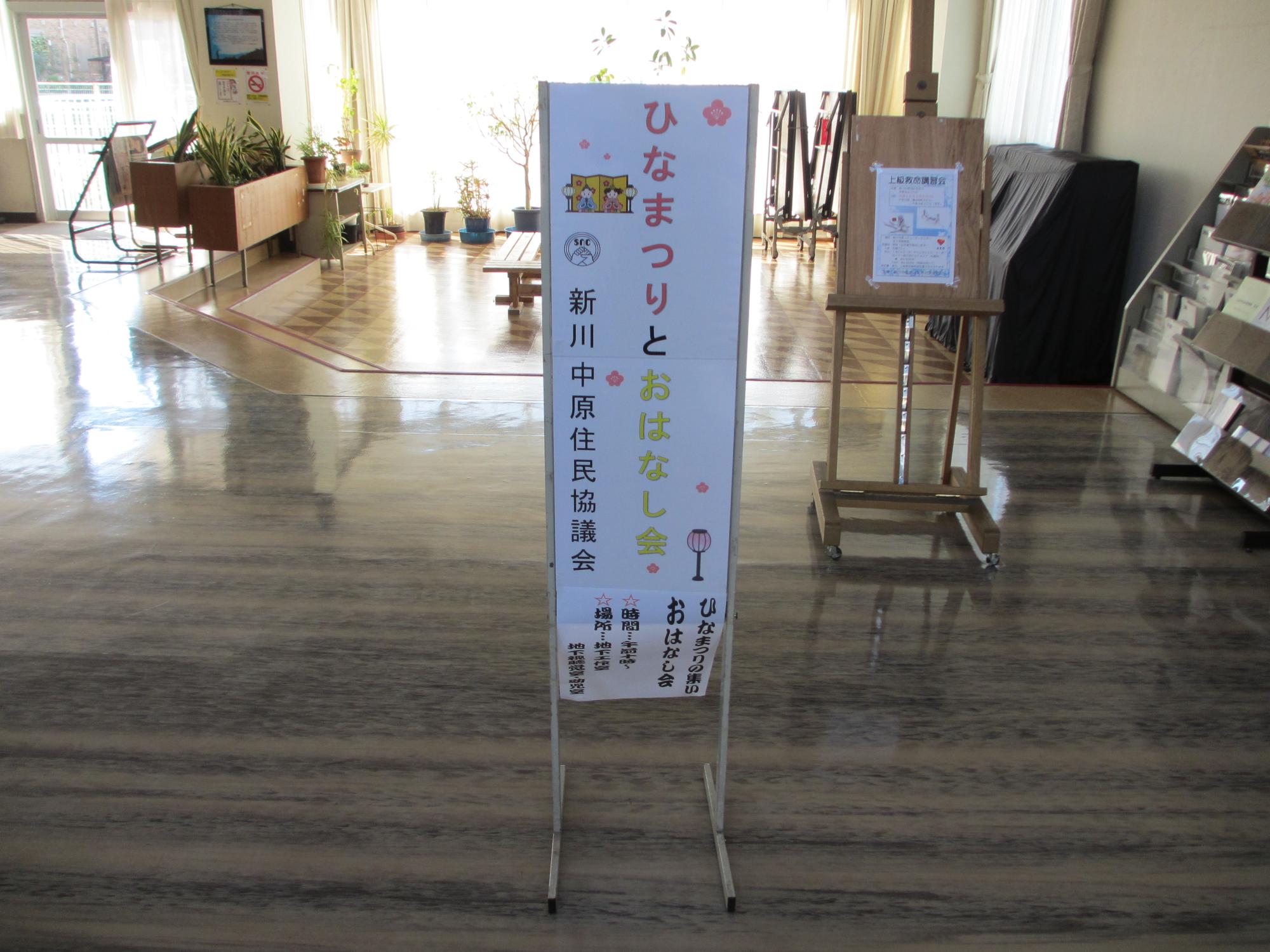 部屋の中に置かれた「ひなまつりとおはなし会」のポスターが貼られた看板の写真