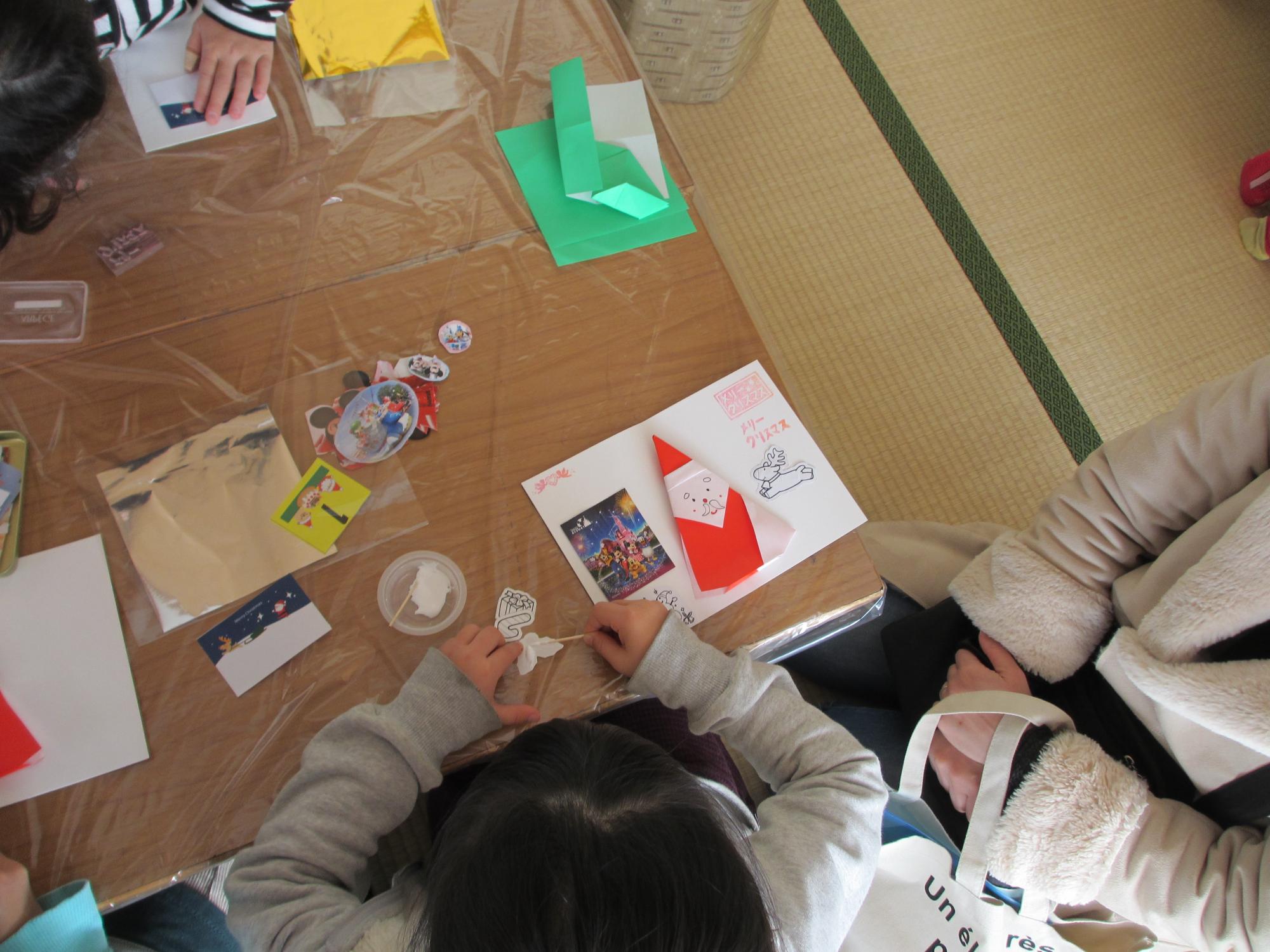 机の上で、糊を紙に付けている子供の写真