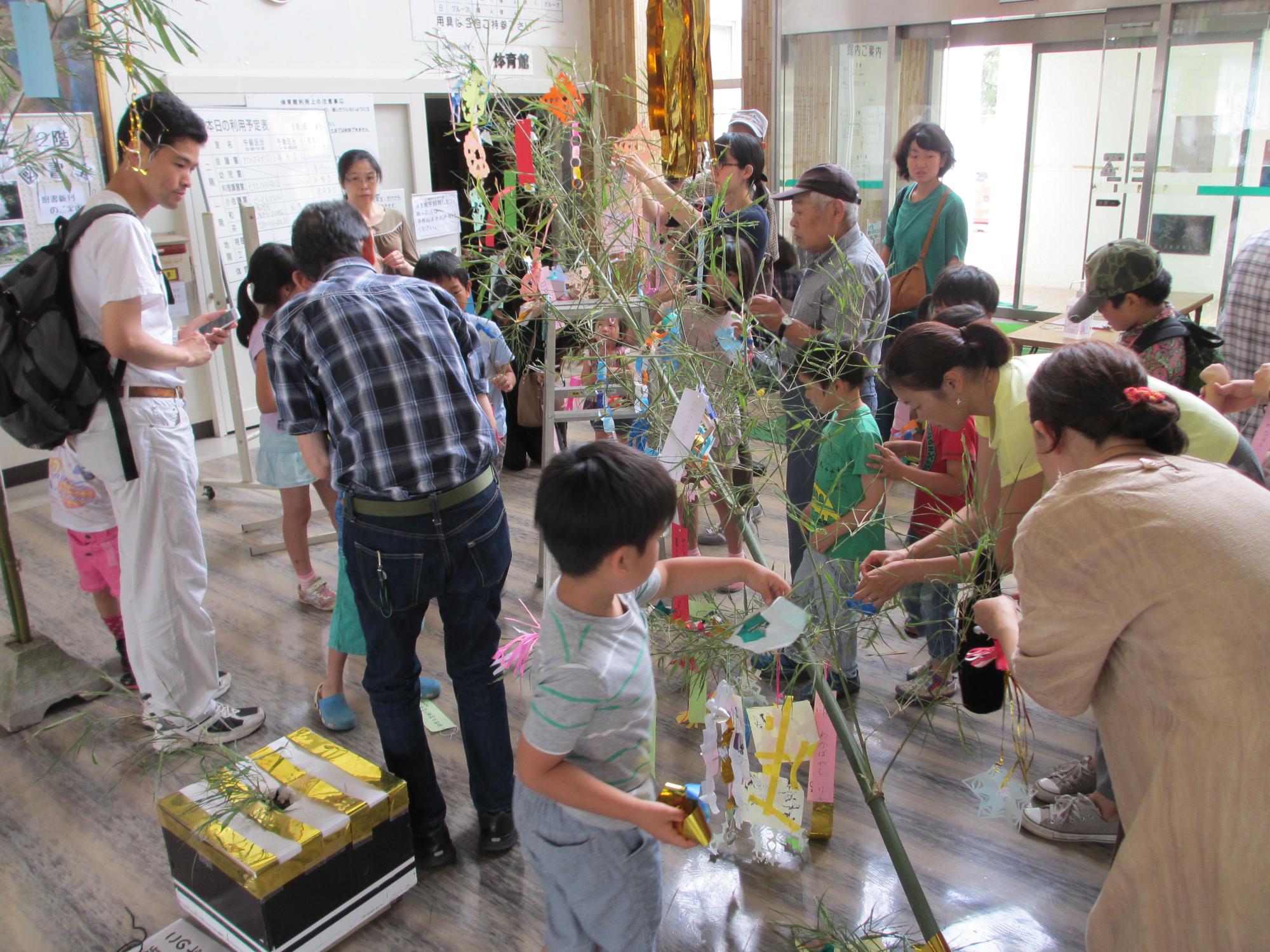 子どもたちがたくさんいる中で、笹飾りをつけている写真