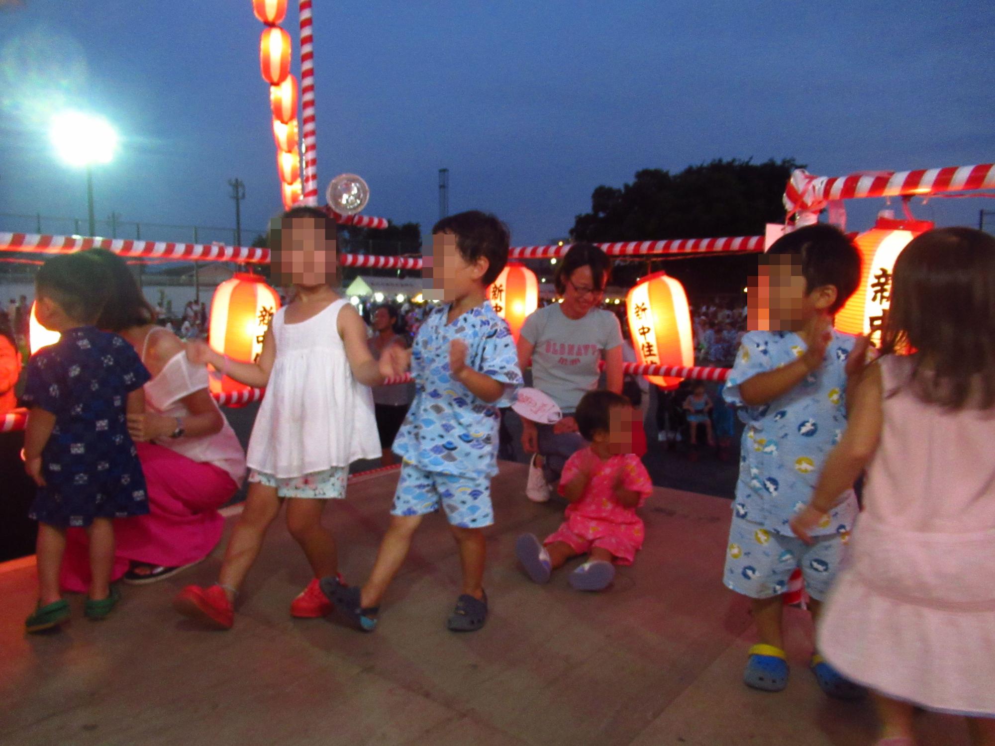 夜にやぐらに登り、踊りを楽しむ子供たちの写真