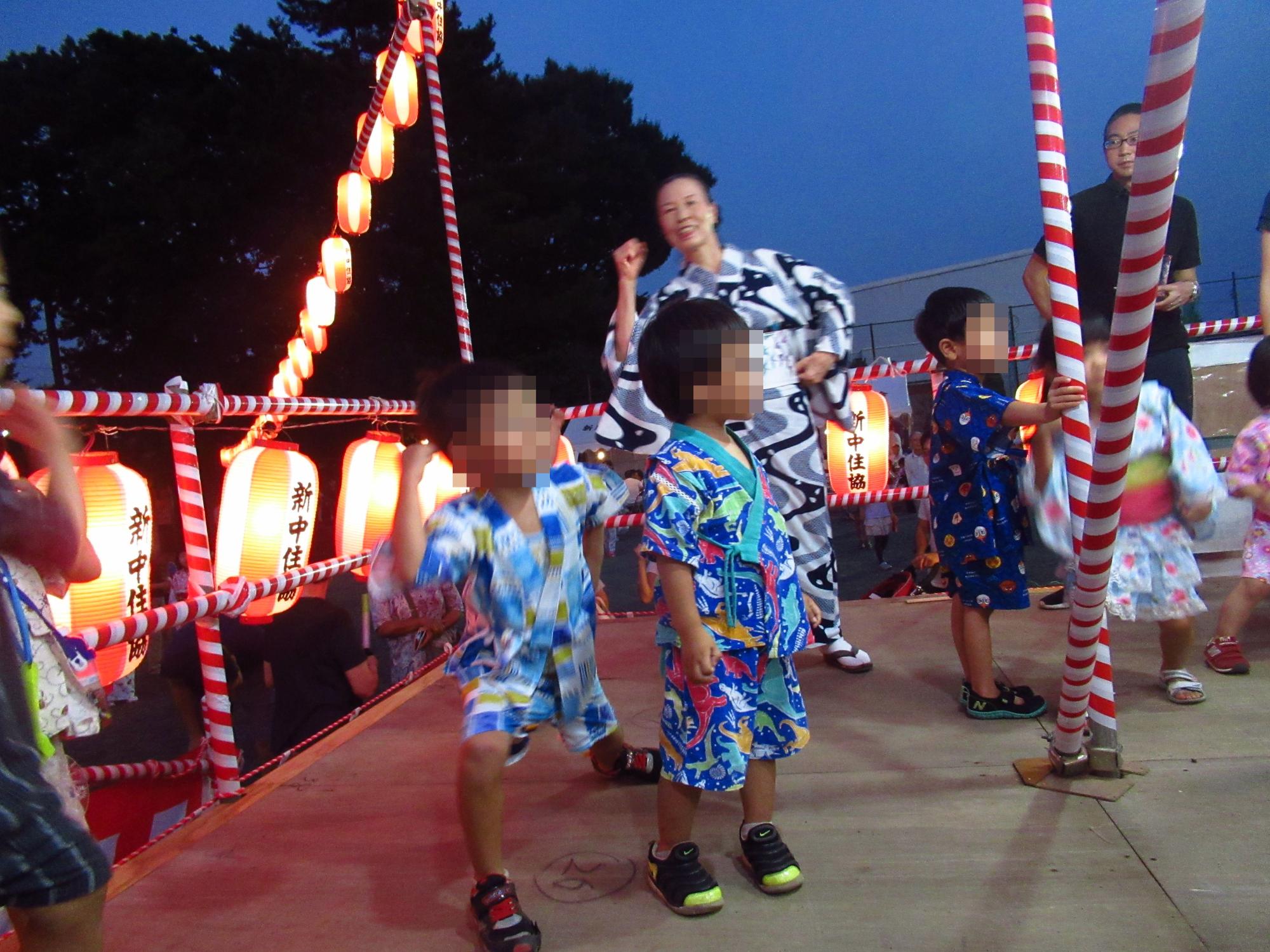 夜にやぐらの上に登り、踊る六人の子供と二人の大人の写真