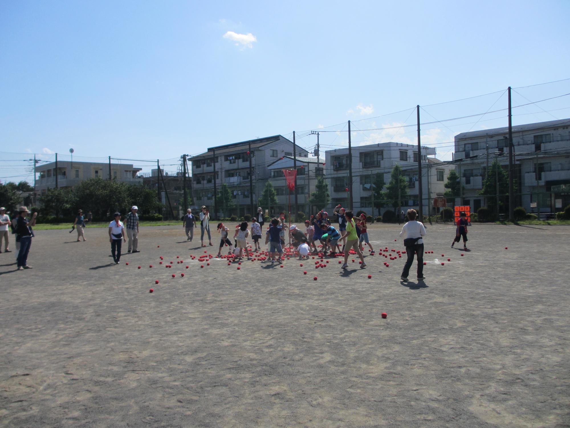 校庭で玉入れを行う大勢の子供たちの写真
