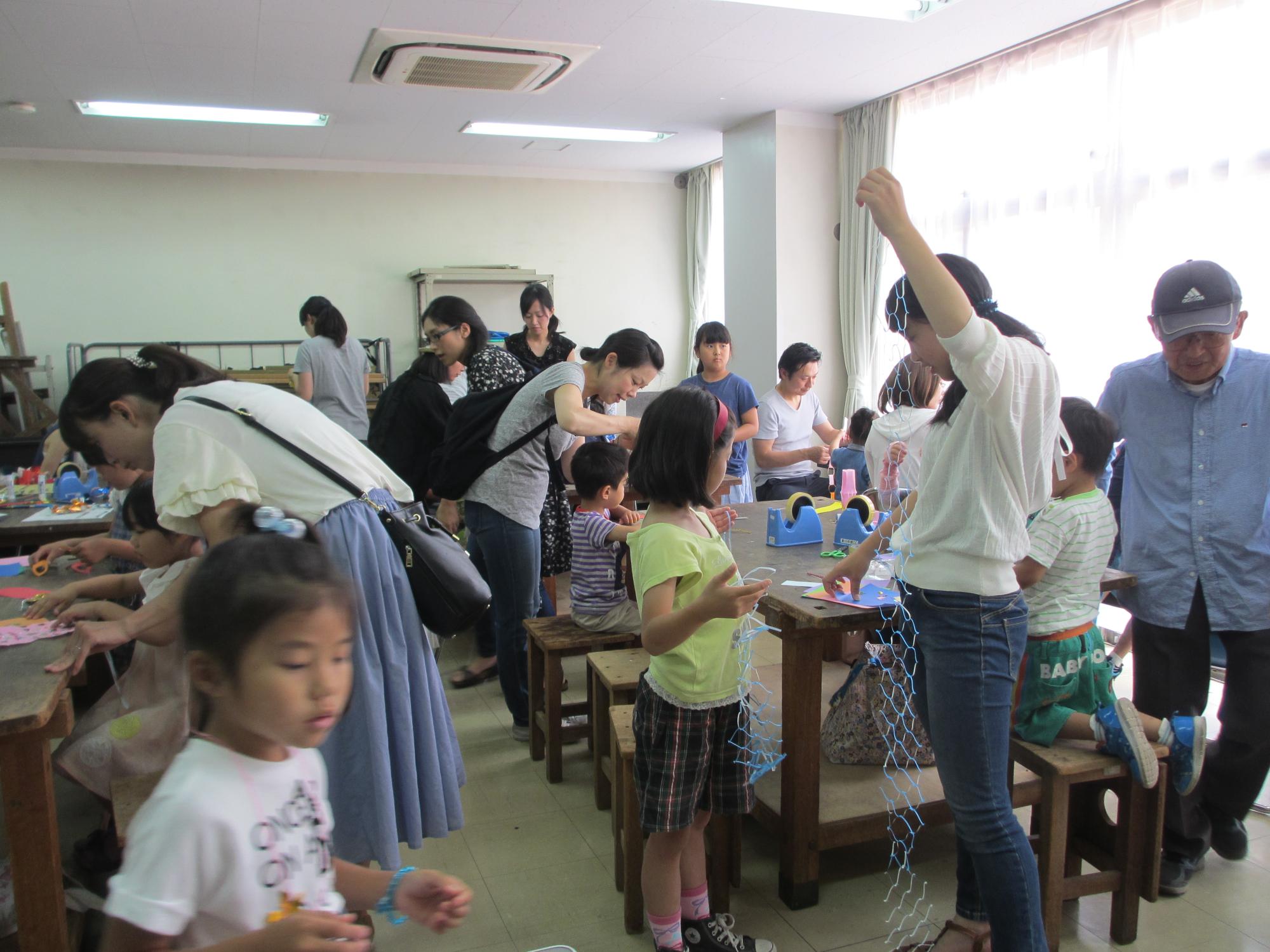 大勢の人々が、紙の飾りを作っているところを写した写真