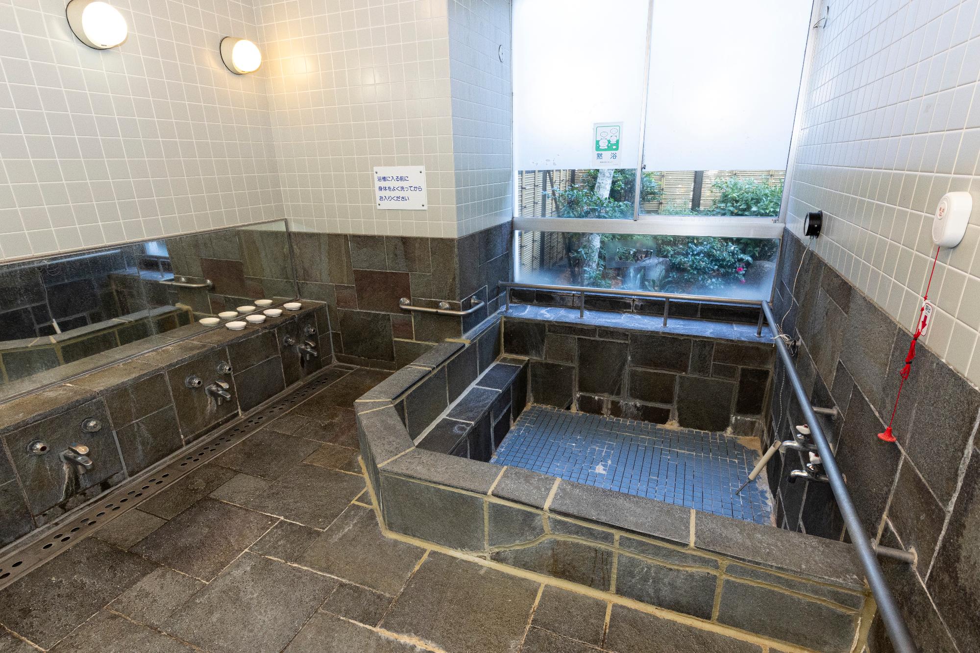 部屋の奥に浴槽と大きな窓がある、浴室を撮った写真