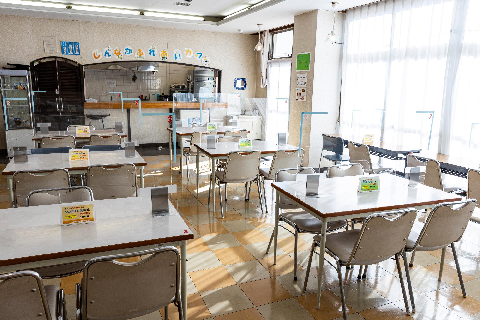 一面が窓になった日当たりの良い部屋の中で、長机と多くの椅子が並べられた部屋の写真