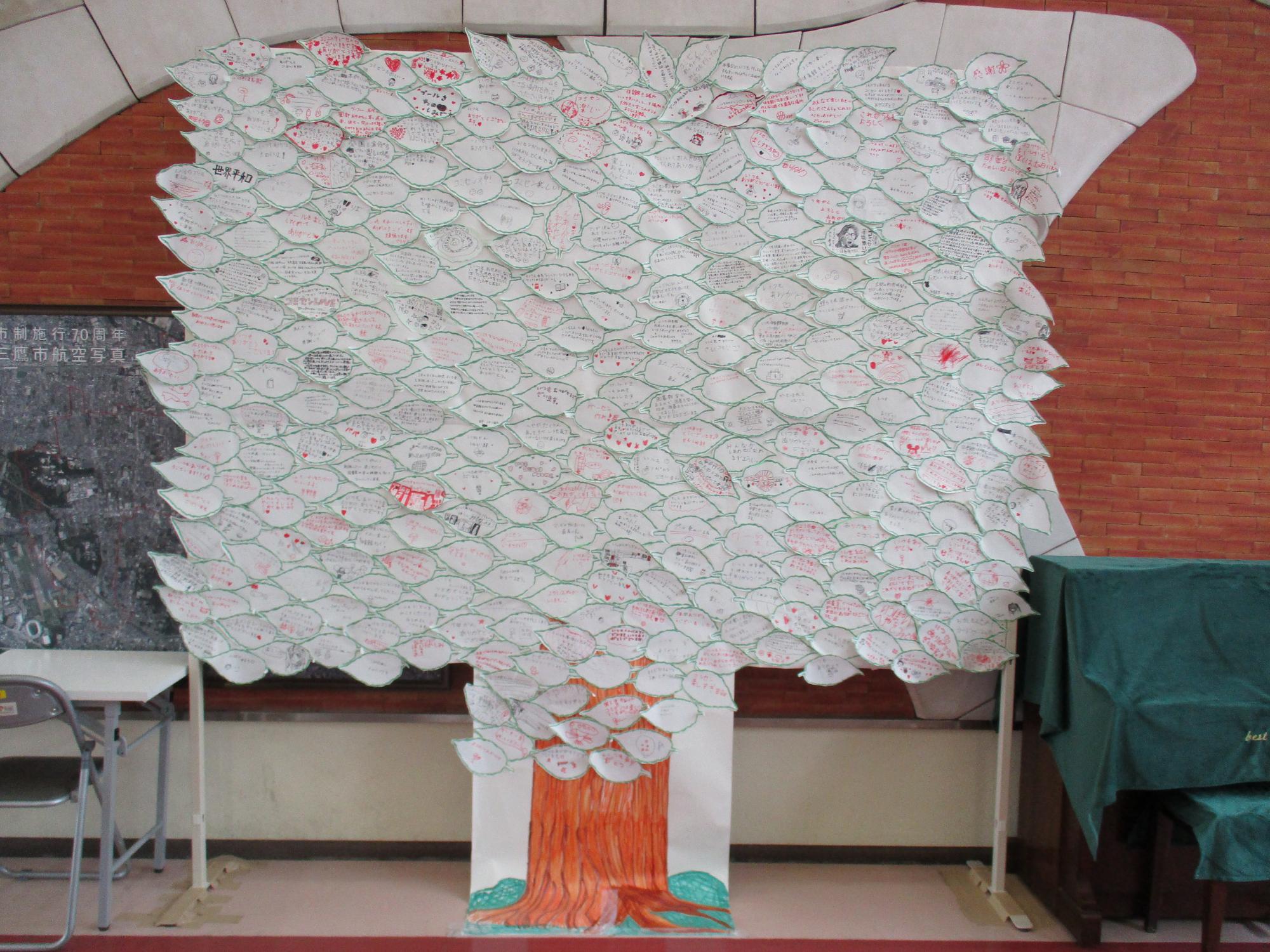 多くのメッセージを書いた紙が寄せられ、葉が生い茂った木のように並べられた展示物「けやき」の写真