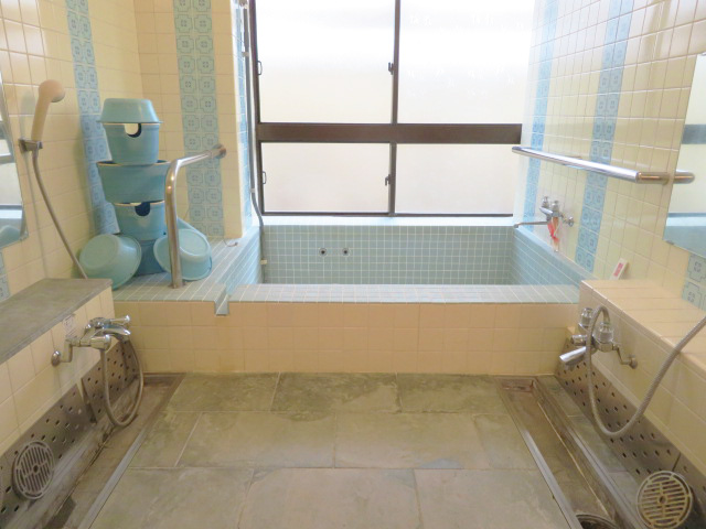 青色のタイルの浴槽と青色の桶が置いてある浴室の写真