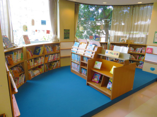 小さい本棚が並んでおり青いマットが引いてある図書室の写真