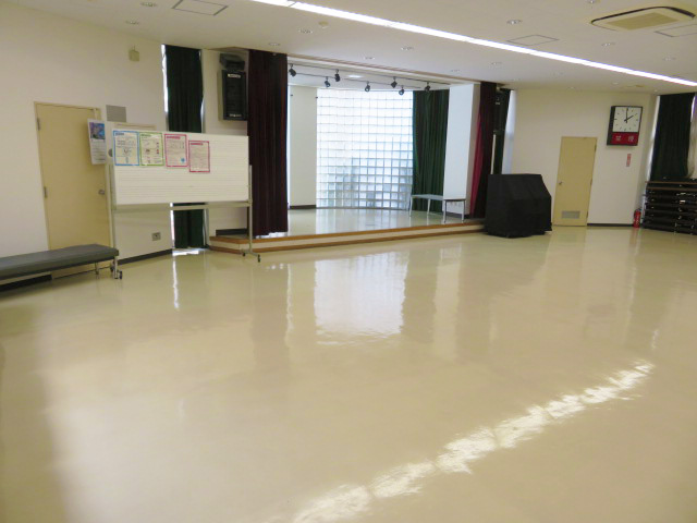 奥に一段上がったステージがある広い大集会室の写真