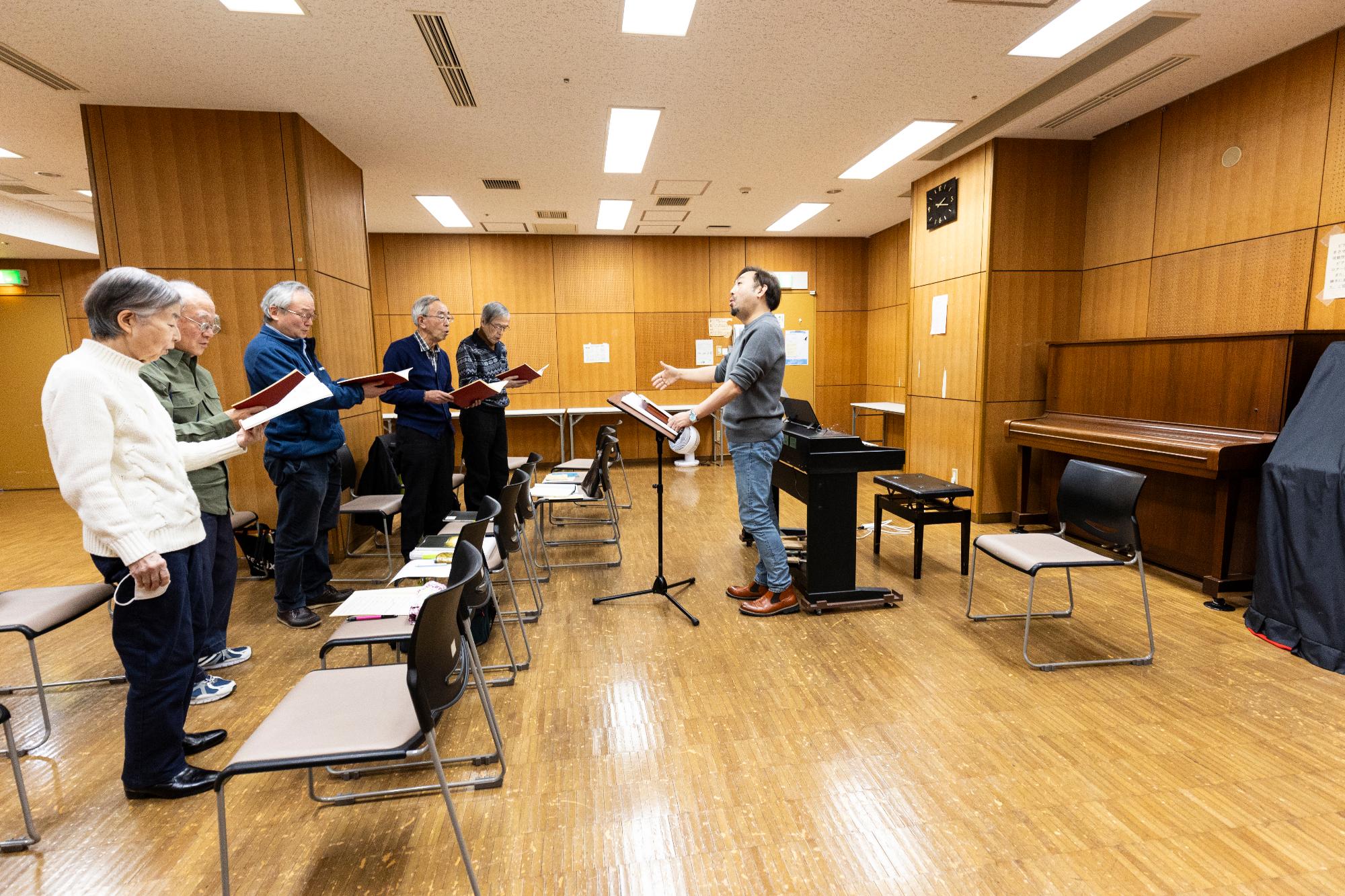 部屋の中でコーラスの練習をする人々の写真